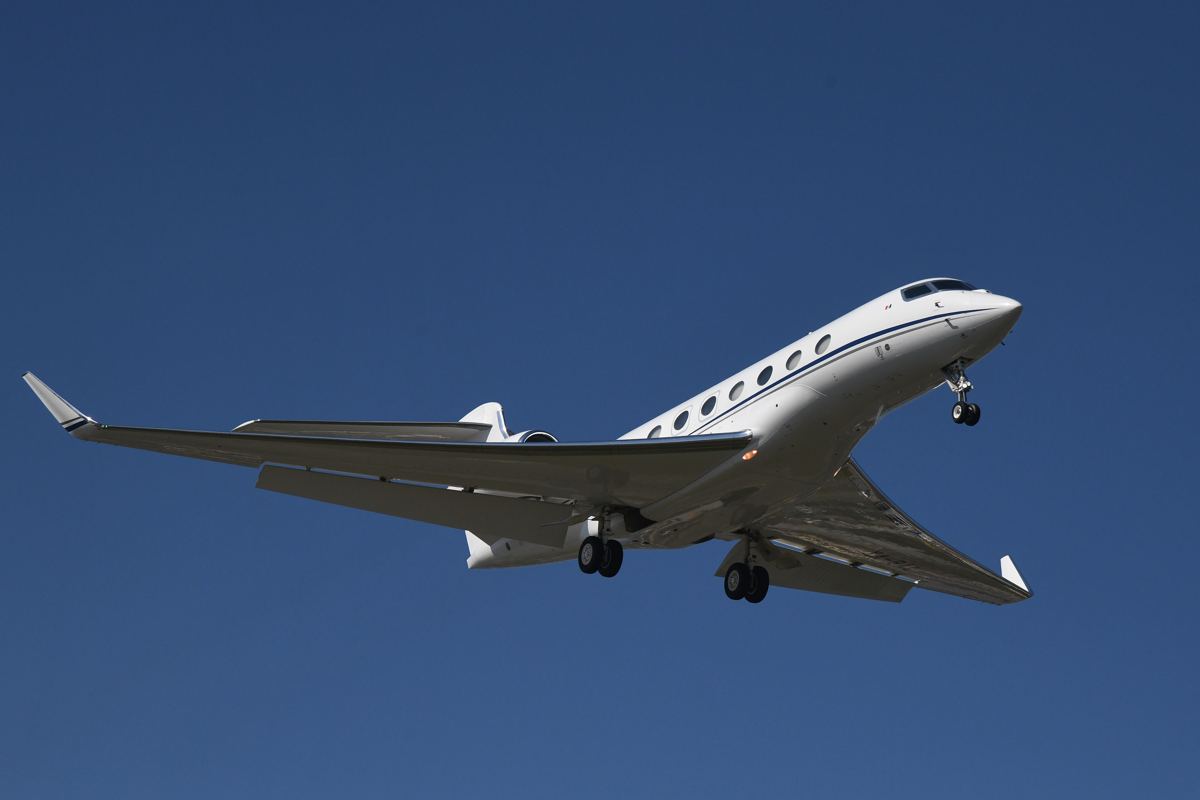 A private business jet climbing into a clear blue sky