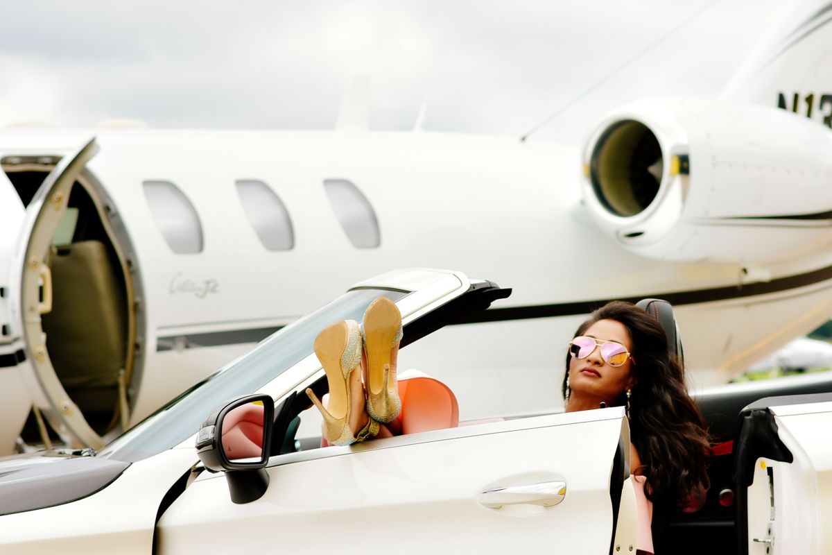 A traveller in a convertible beside a private jet