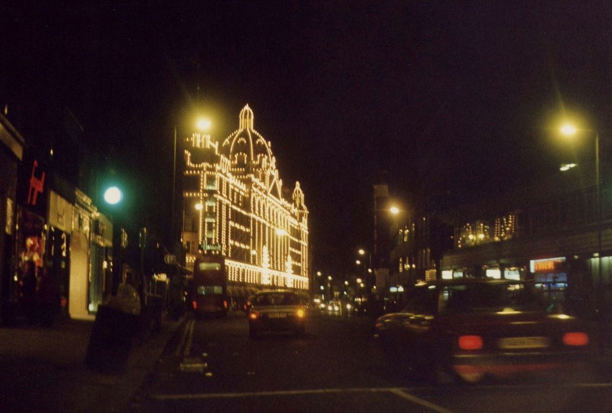 Harrods in Knightsbridge illuminated at night with traffic passing