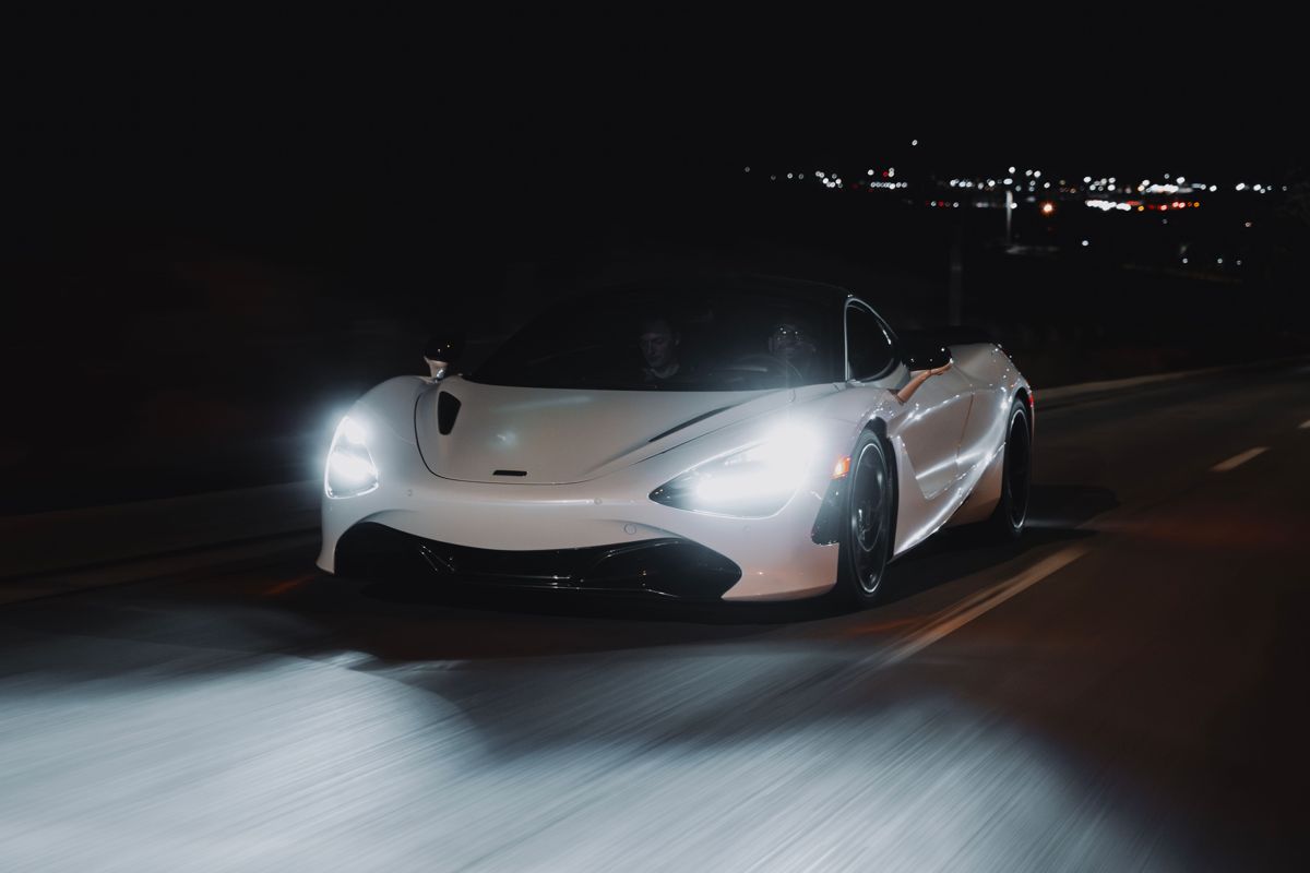 White McLaren with headlights on at night